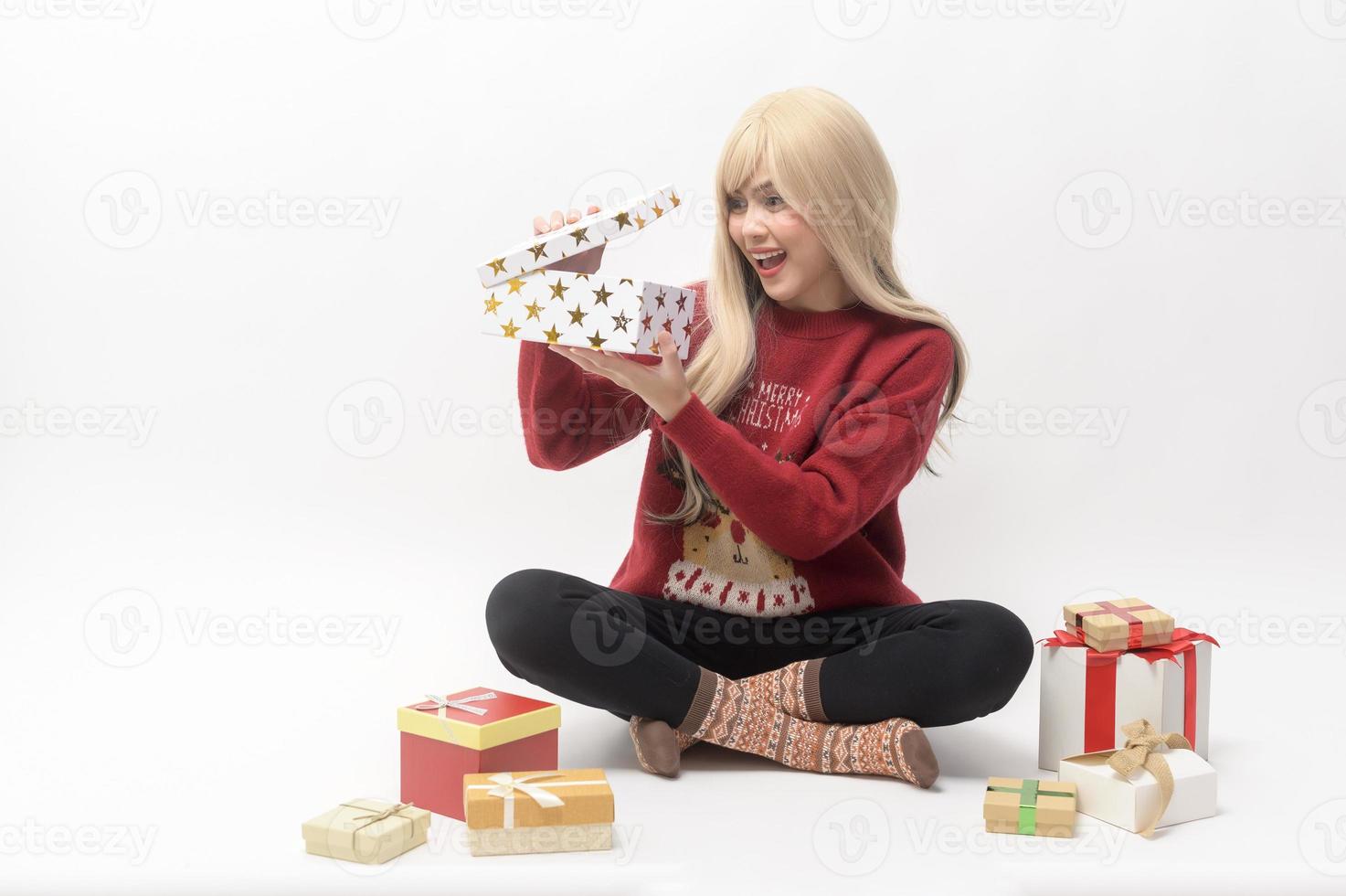 Portrait of happy Caucasian young woman in in Christmas sweater with gift box and shopping bags over white background photo