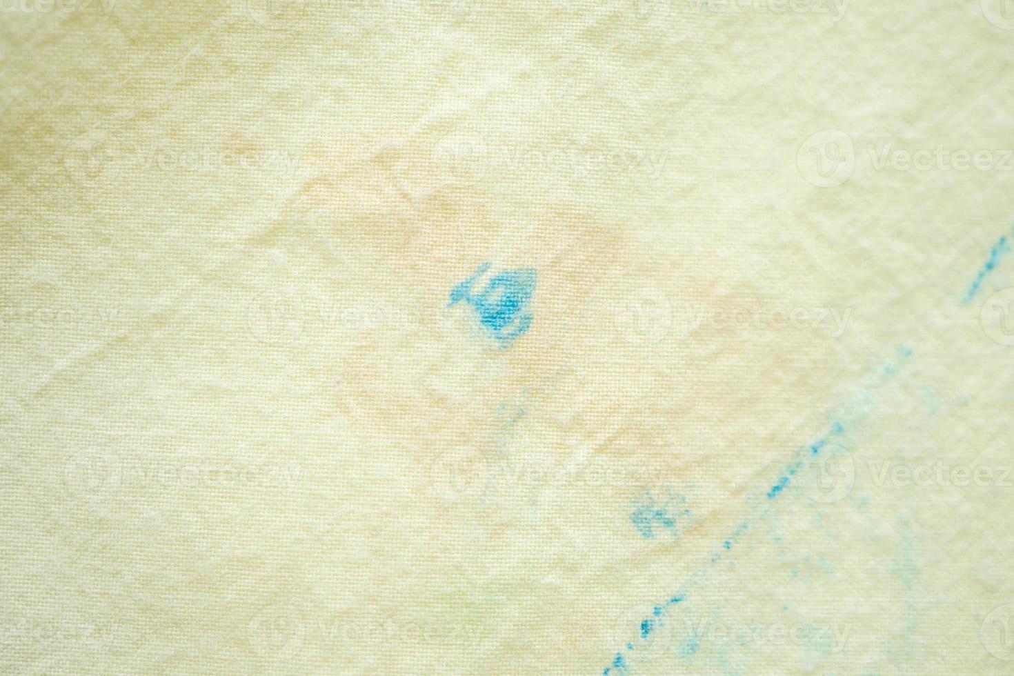 dirty color stain on yellow fabric texture background photo