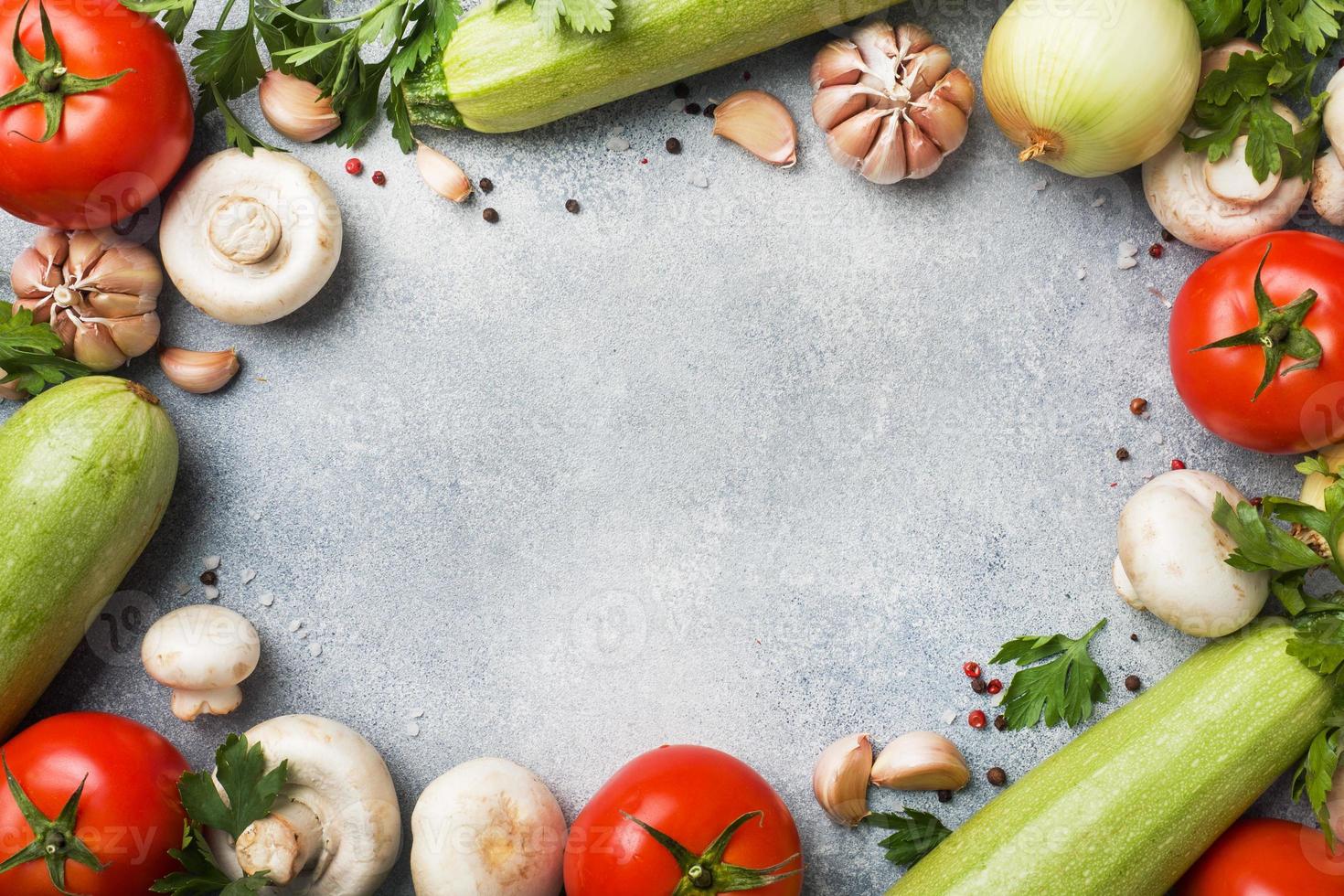 Set of different seasonal vegetables on a gray concrete background. Tomato zucchini onion garlic mushrooms parsley spices. Frame copy space. photo