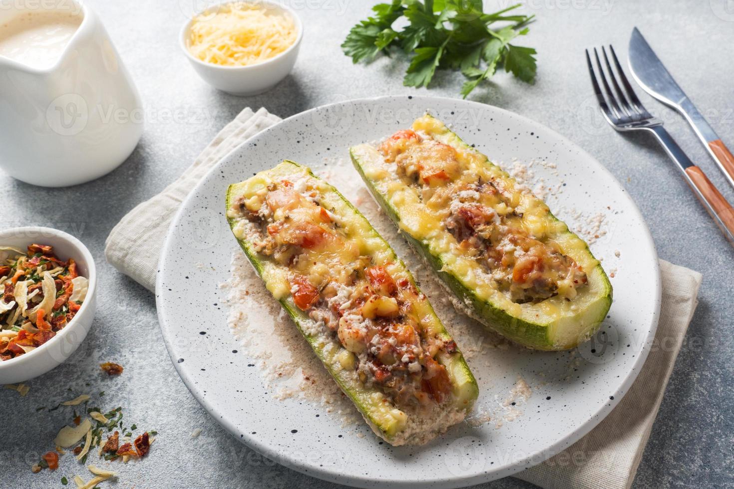 Baked stuffed zucchini boats with minced chicken mushrooms and vegetables with cheese on a plate. photo