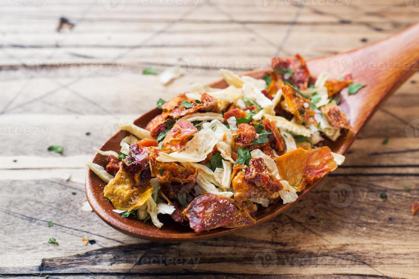 Dried spices, sun-dried tomatoes, dried carrots, Basil and Provencal herbs in a wooden spoon on a wooden table. Copy space. photo