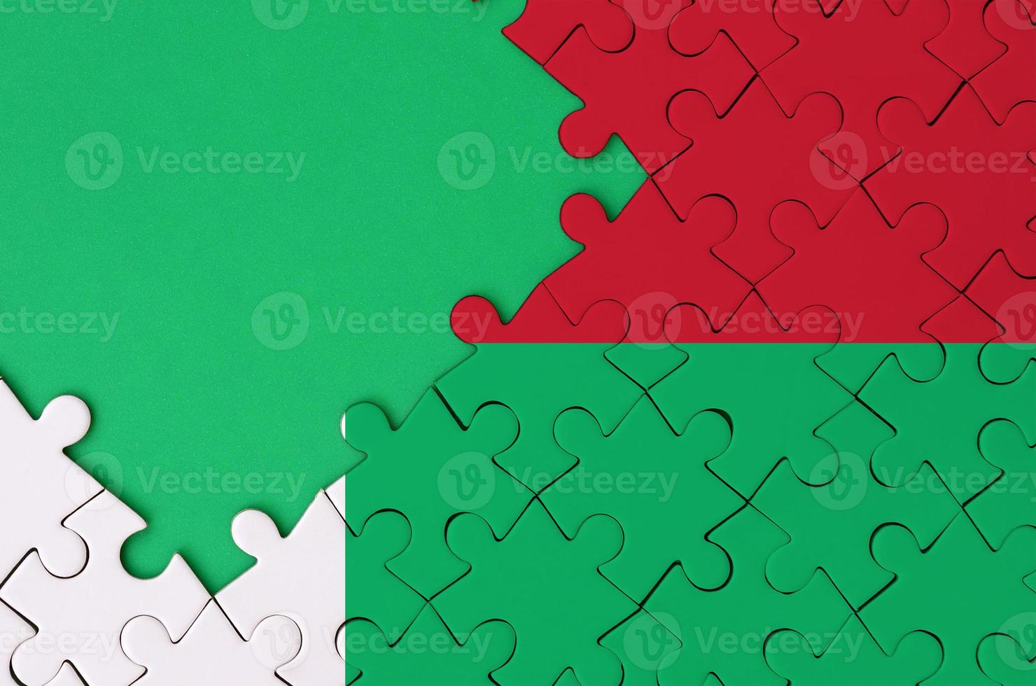 Madagascar flag  is depicted on a completed jigsaw puzzle with free green copy space on the left side photo