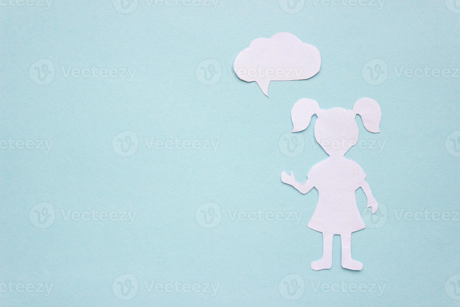 The silhouette of a girl in a dress and with ponytails made of white paper, cut by hand. With speech-bubble in the right side of the photo. With copy space photo