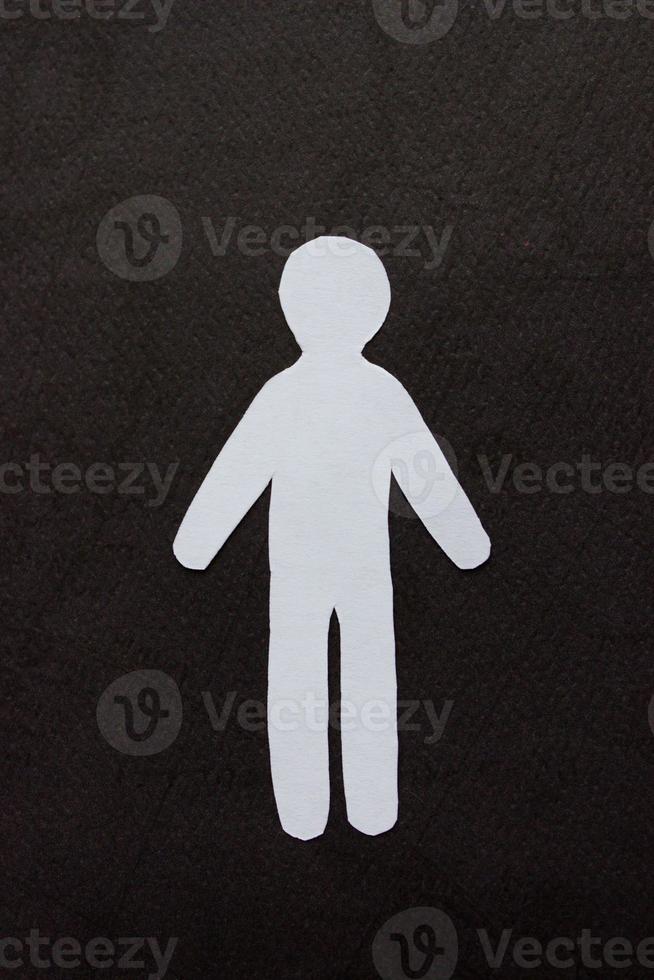 Silhouette of a man of white paper, cut by hand on black background photo