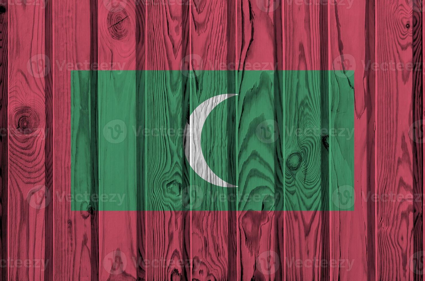 Maldives flag depicted in bright paint colors on old wooden wall. Textured banner on rough background photo