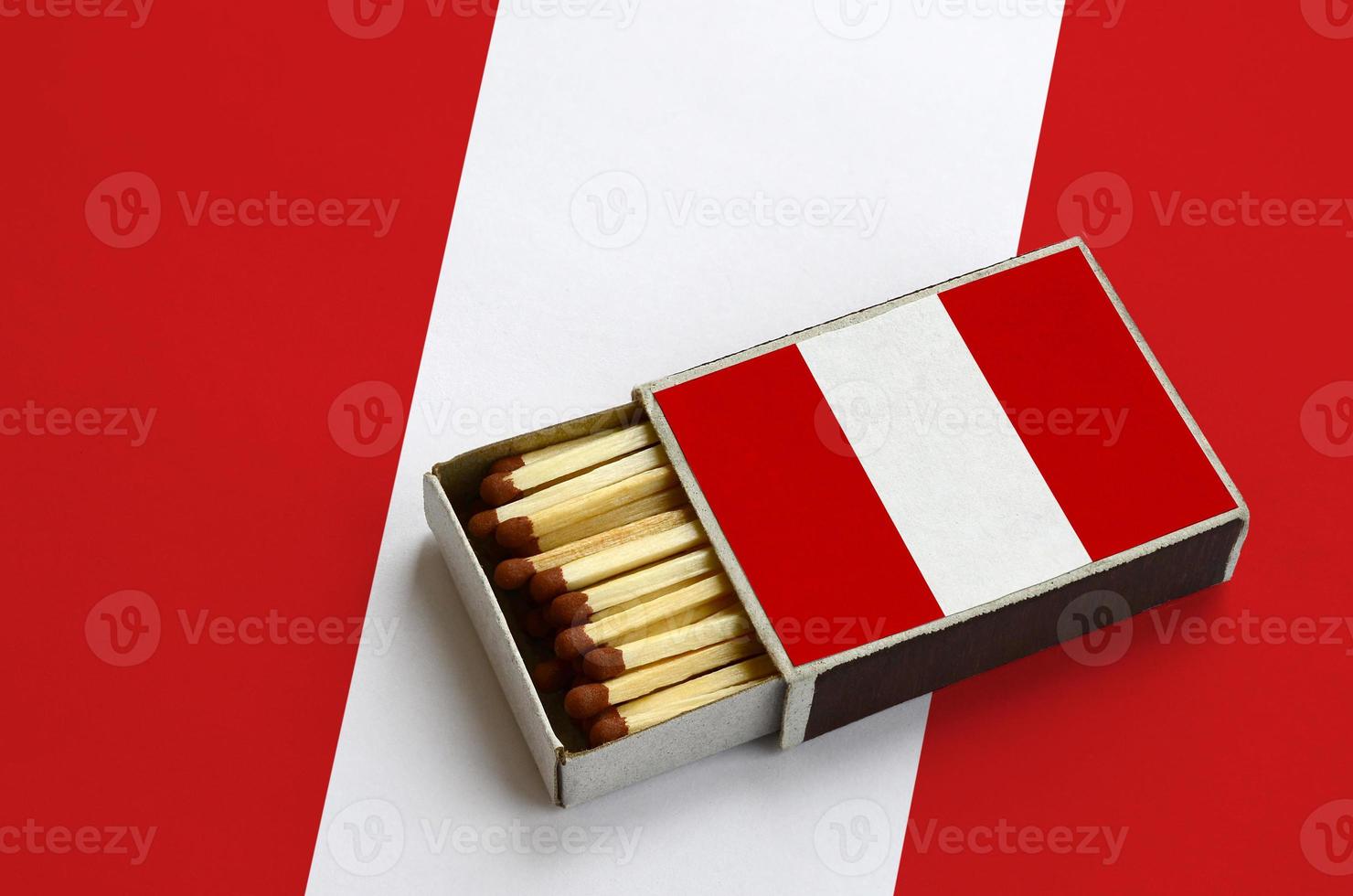 Peru flag  is shown in an open matchbox, which is filled with matches and lies on a large flag photo