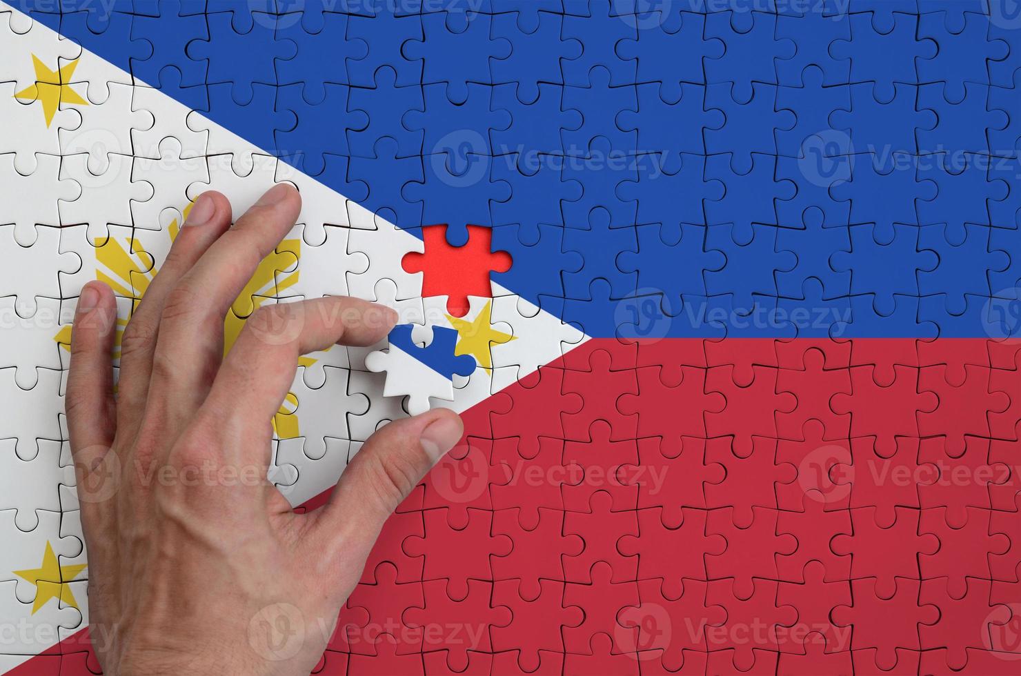 Philippines flag  is depicted on a puzzle, which the man's hand completes to fold photo