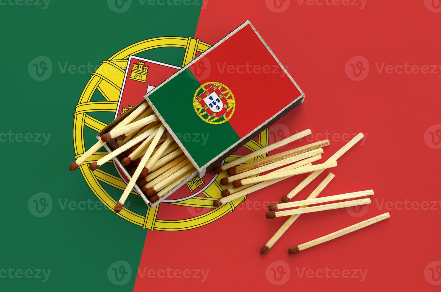 Portugal flag  is shown on an open matchbox, from which several matches fall and lies on a large flag photo