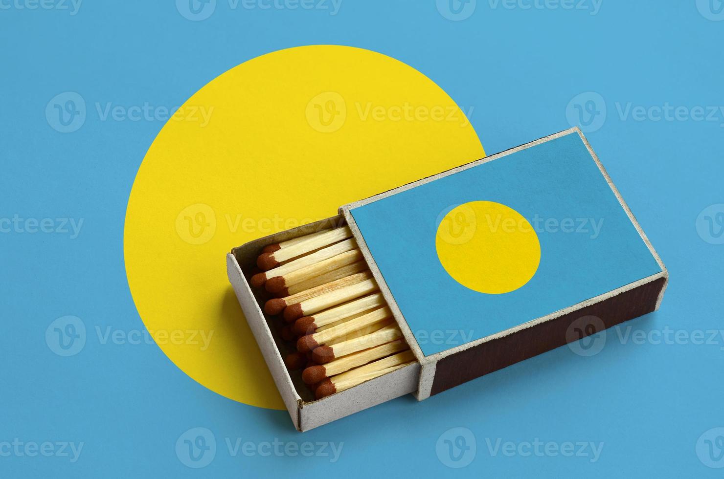 Palau flag  is shown in an open matchbox, which is filled with matches and lies on a large flag photo