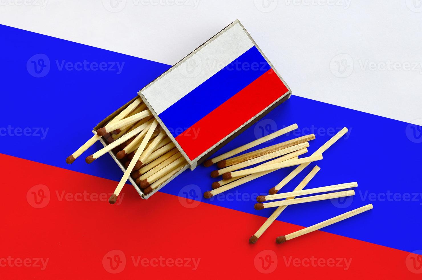 Russia flag  is shown on an open matchbox, from which several matches fall and lies on a large flag photo