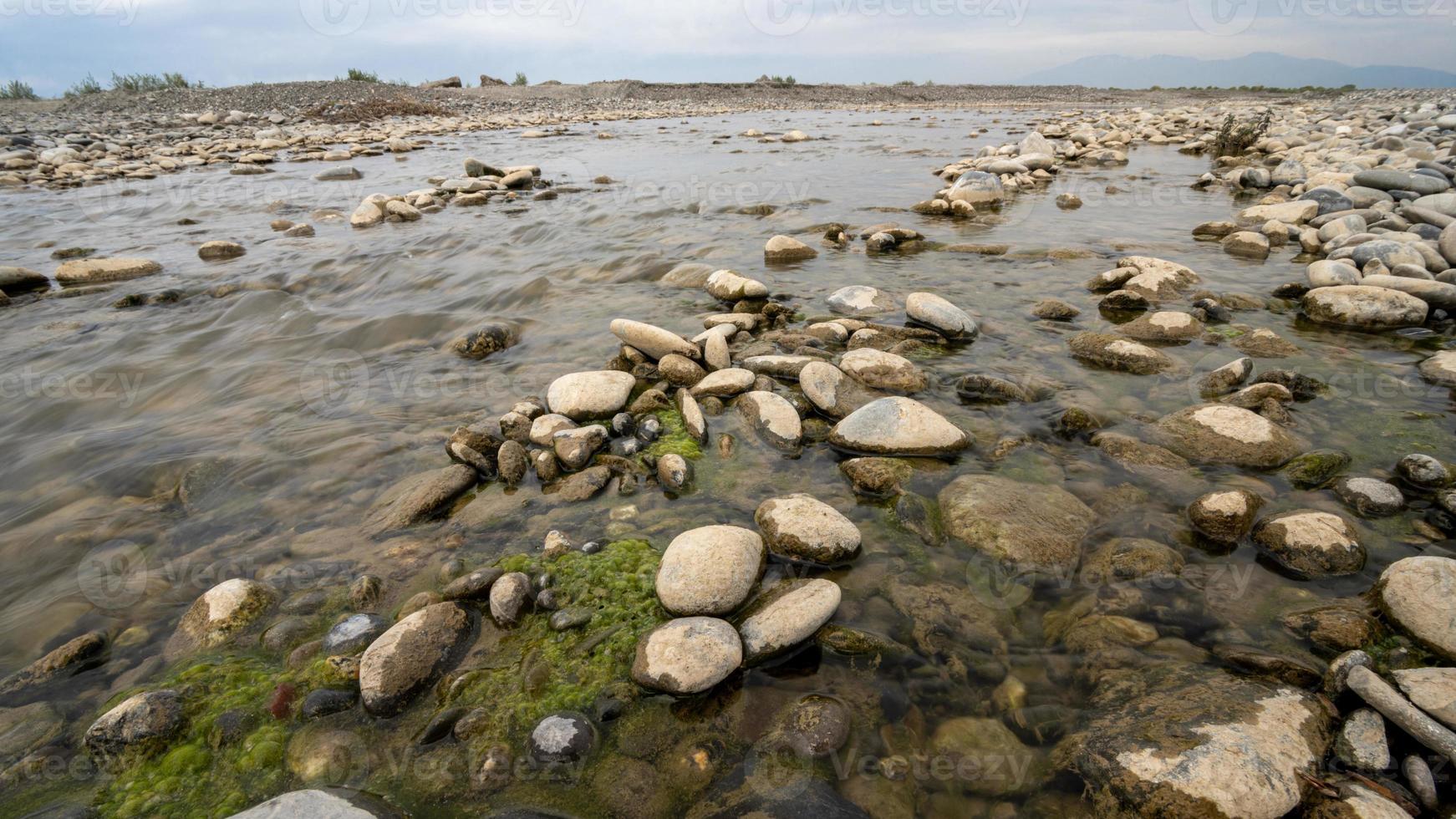 A closeup of beautiful big and small wet stones in a lake in a rural area photo