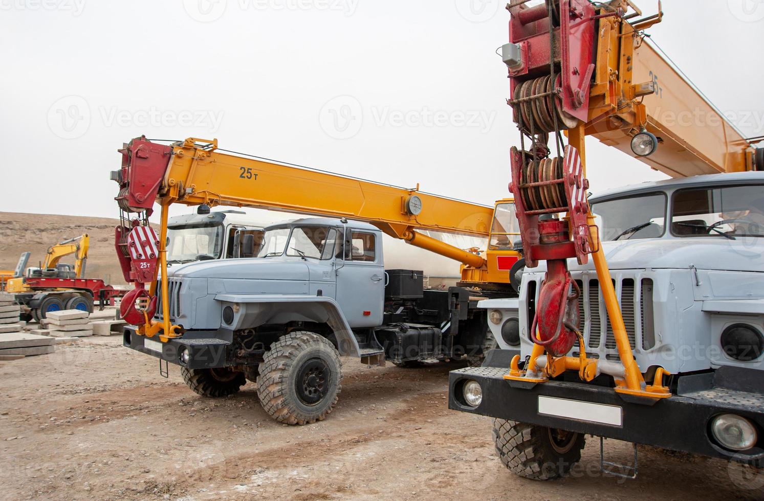 A row of large truck cranes and machines at an industrial construction site photo