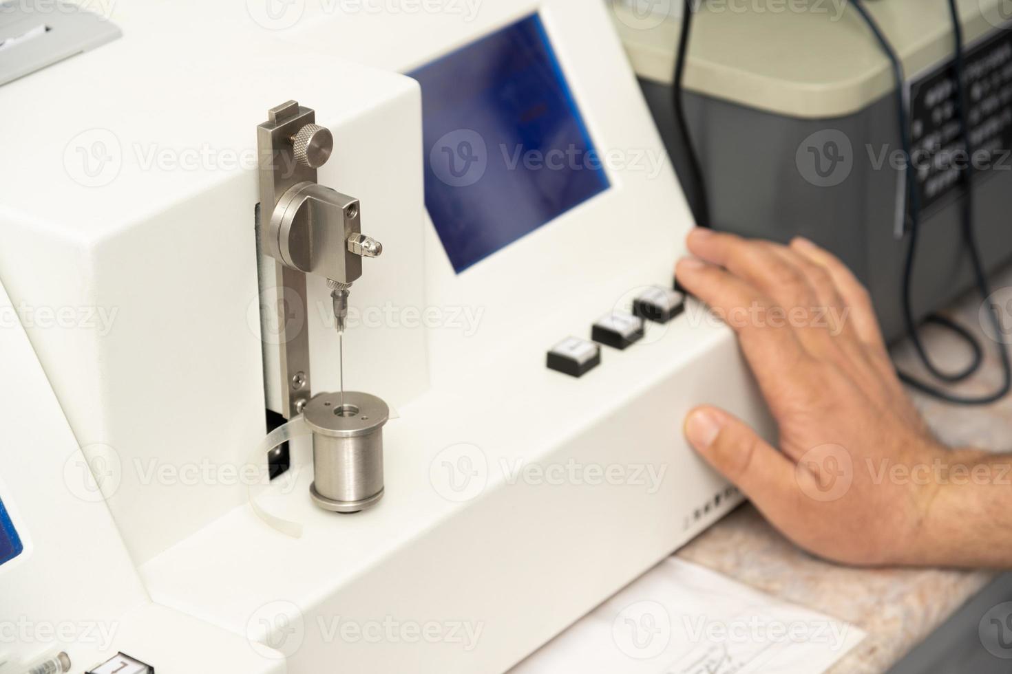 A closeup shot of a hand using a medical machine to test and manufacture pharmaceutical syringes photo