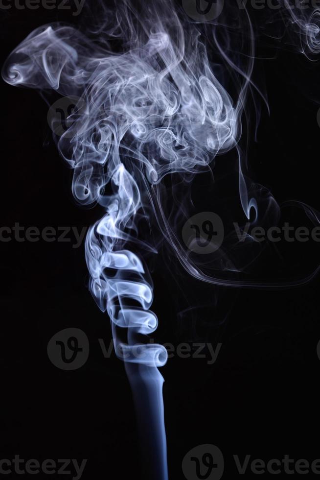 un disparo vertical de humo de tabaco azul sobre un fondo negro foto