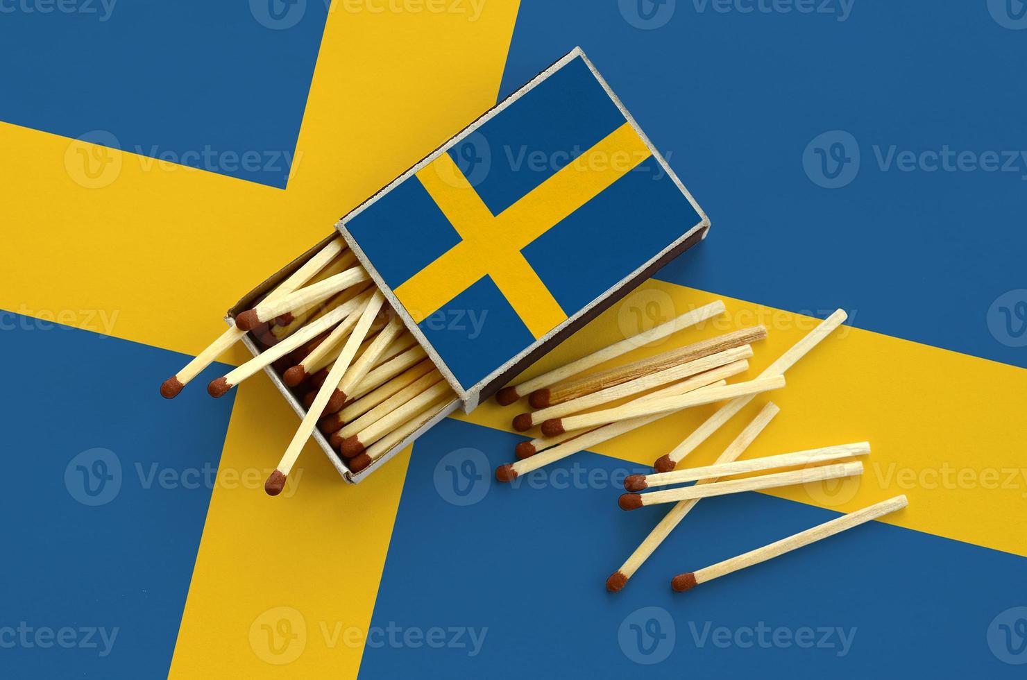 Sweden flag  is shown on an open matchbox, from which several matches fall and lies on a large flag photo