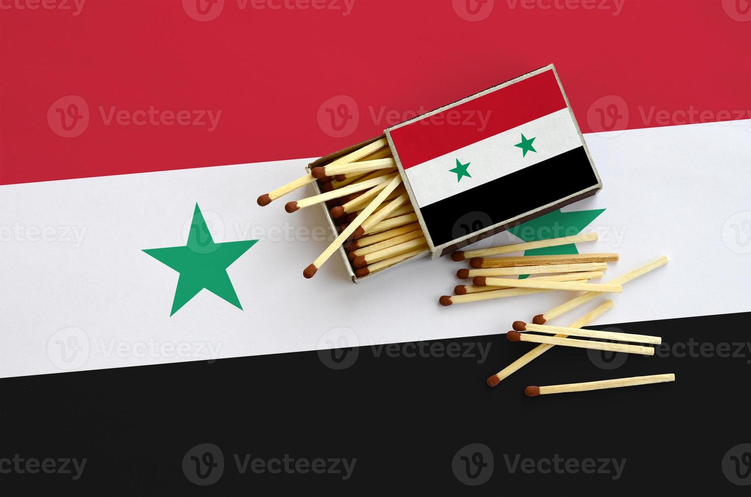 Syria flag  is shown on an open matchbox, from which several matches fall and lies on a large flag photo