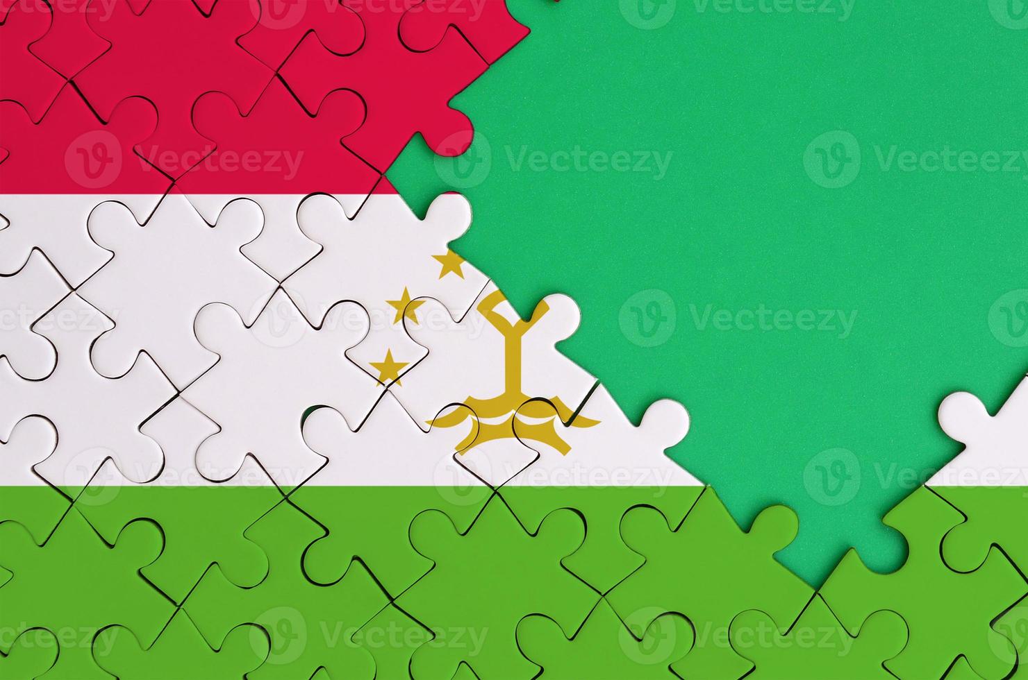 Tajikistan flag  is depicted on a completed jigsaw puzzle with free green copy space on the right side photo