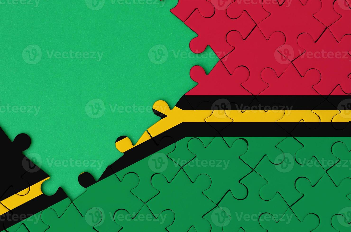 Vanuatu flag  is depicted on a completed jigsaw puzzle with free green copy space on the left side photo