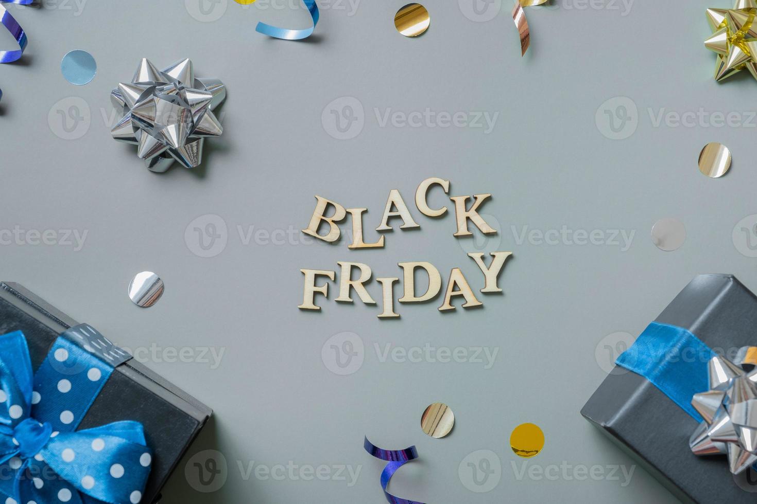 Black friday text with gifts and festive tinsel flat lay photo