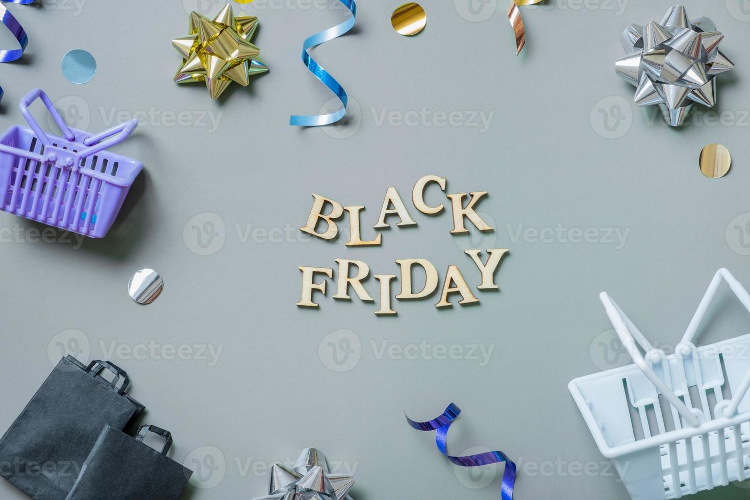 Black friday text with gifts, shopping baskets and bags and festive tinsel flat lay photo