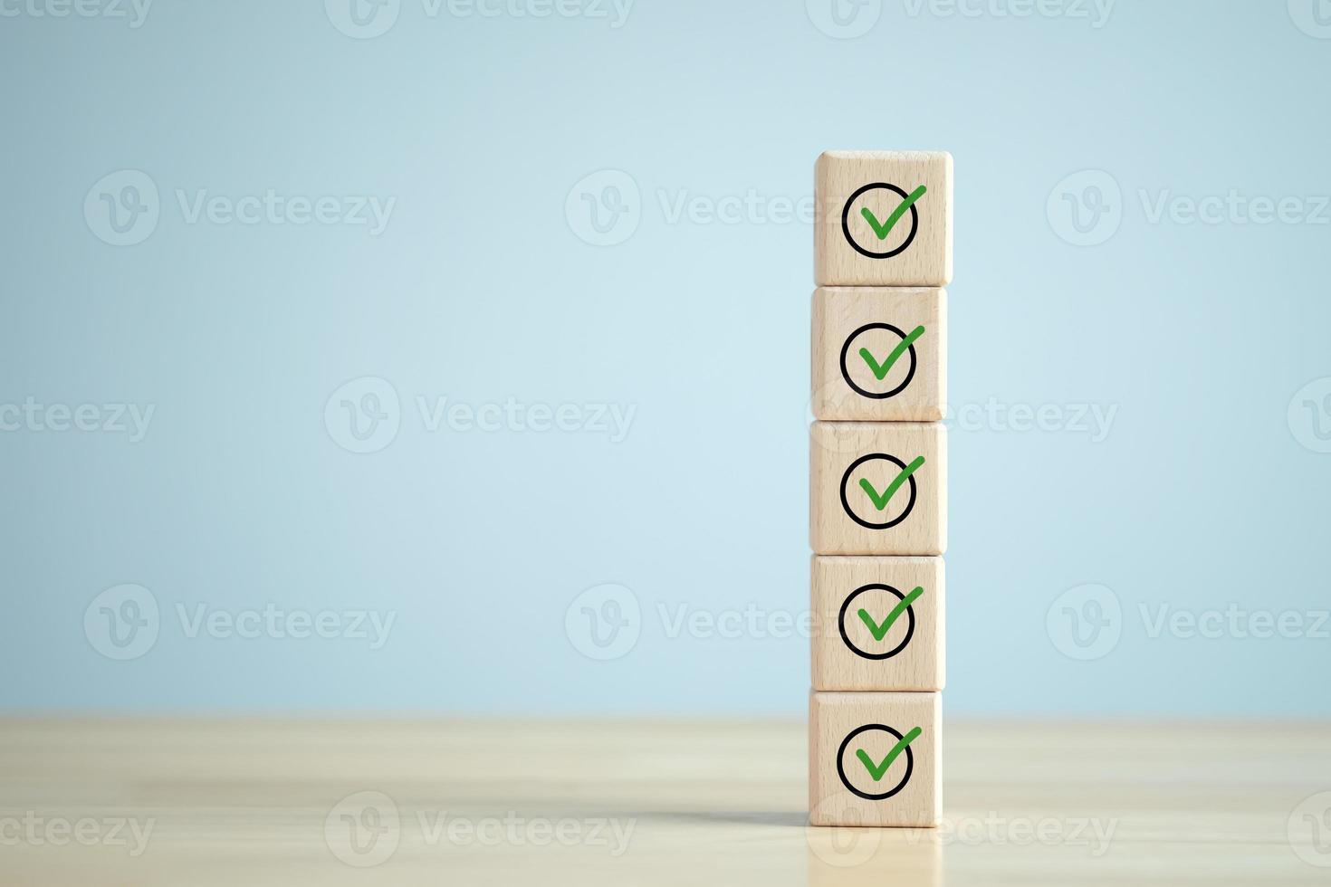 Checklist, Task list, Survey and assessment. Quality Control. Goals achievement and business success. Green check mark icon on wooden blocks. photo