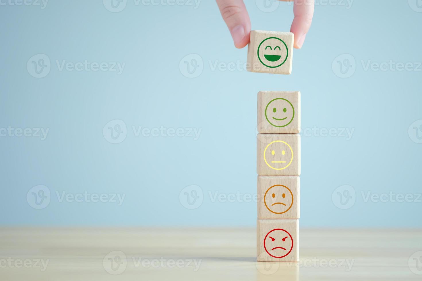 mano eligiendo cara feliz de muchas emociones en bloques de madera. pensamiento positivo, comentarios, satisfacción, revisión del servicio al cliente, evaluación de la salud mental, concepto del día mundial de la salud mental. foto