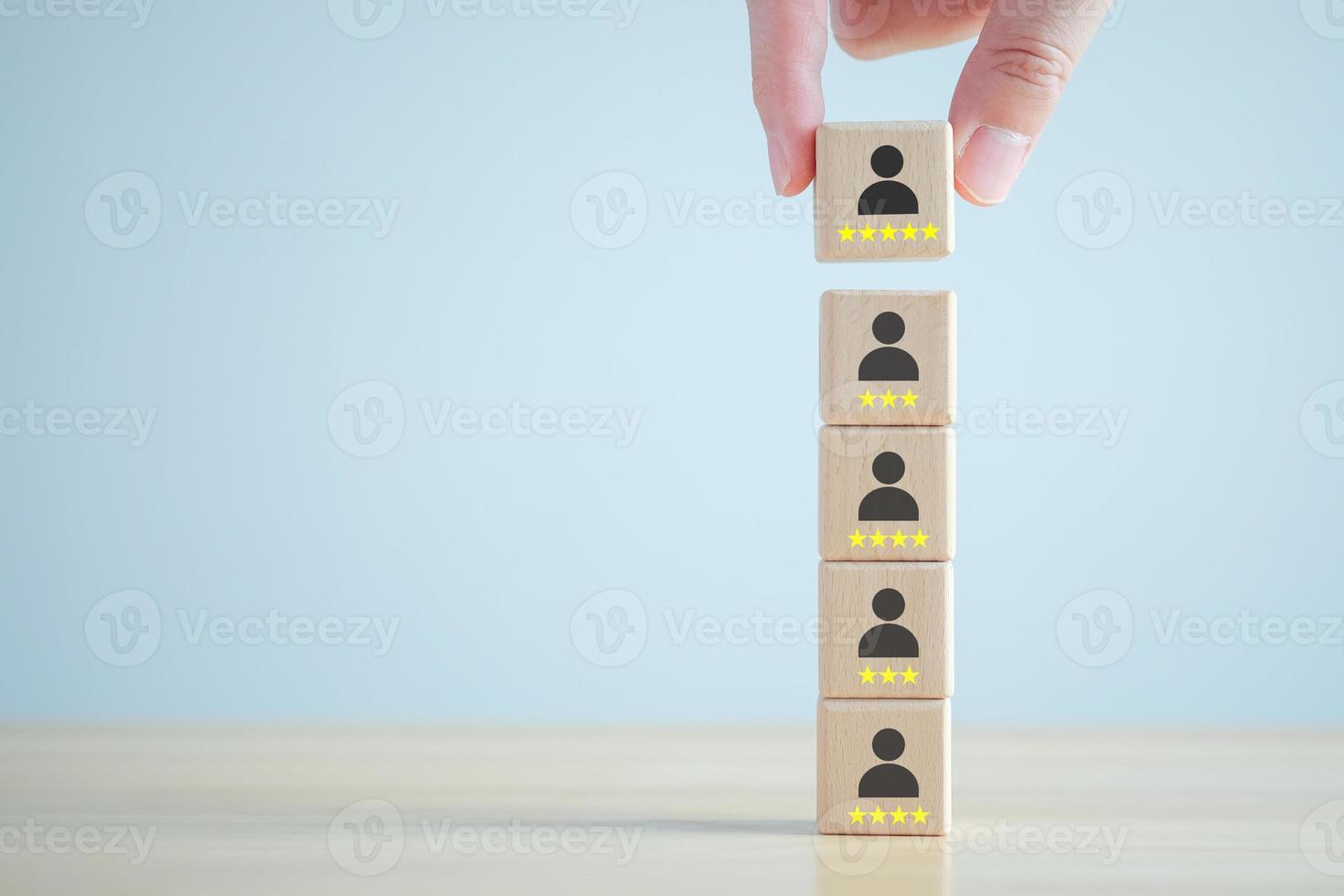 Business hiring and recruitment selection. Career opportunity. Human Resource Management. Hand choosing human icon on wooden block with 5 star. Choice of employee leader from many people. photo