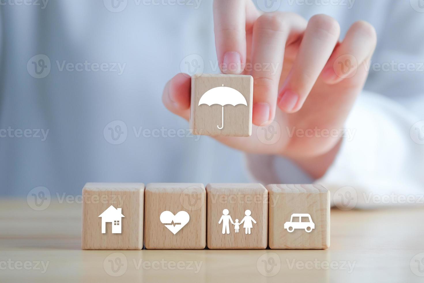 Insurance concept. Protection against a possible eventuality. Hand holding umbrella icon and House, Car, Family and Health icon on wooden block for assurance life concept. photo