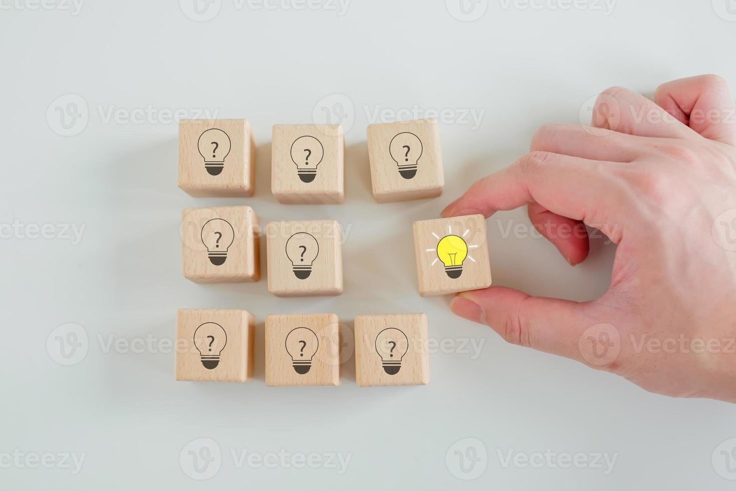 concepto de idea y creatividad. individualidad, singularidad, diferenciación, proceso creativo y solución de problemas. elija a mano la idea de una bombilla brillante de muchas bombillas con un signo de interrogación en bloques de madera. foto