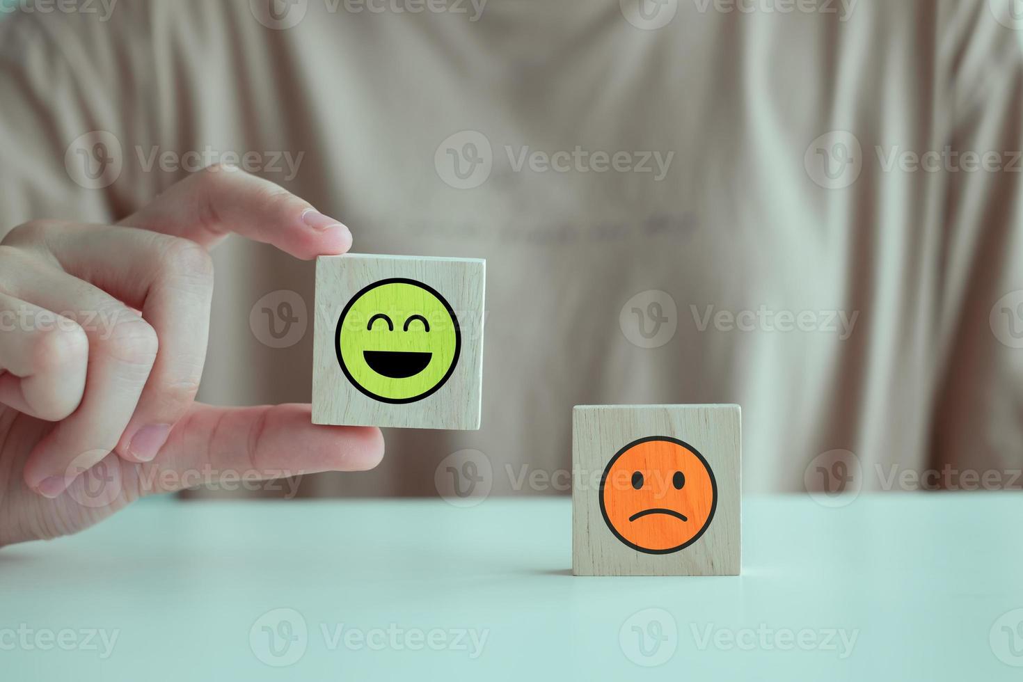 Hand holding happy face from unhappy face on wooden block. Positive thinking, Emotion, Feedback, Satisfaction, Customer service review, Mental health assessment, World mental health day concept. photo