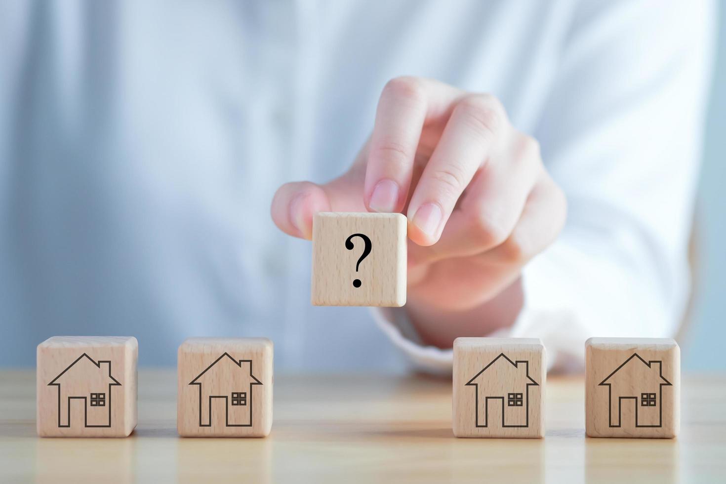 Real estate, Property investment and asset management concept. Hand holding question mark and house on wooden blocks. Decision to choose the best property with your right. Choosing suitable housing. photo