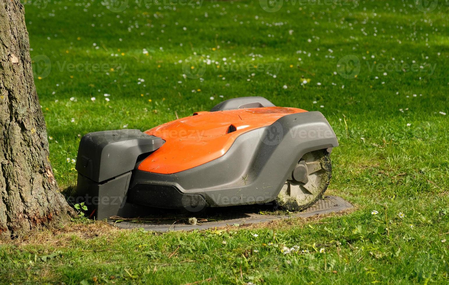 Robotic Lawn Mower on green grass background.Automatic robot lawnmower in modern garden.Green grass trimming with lawn mower. Close-up view of the lawn mower dirty blade after mowing the lawn. photo