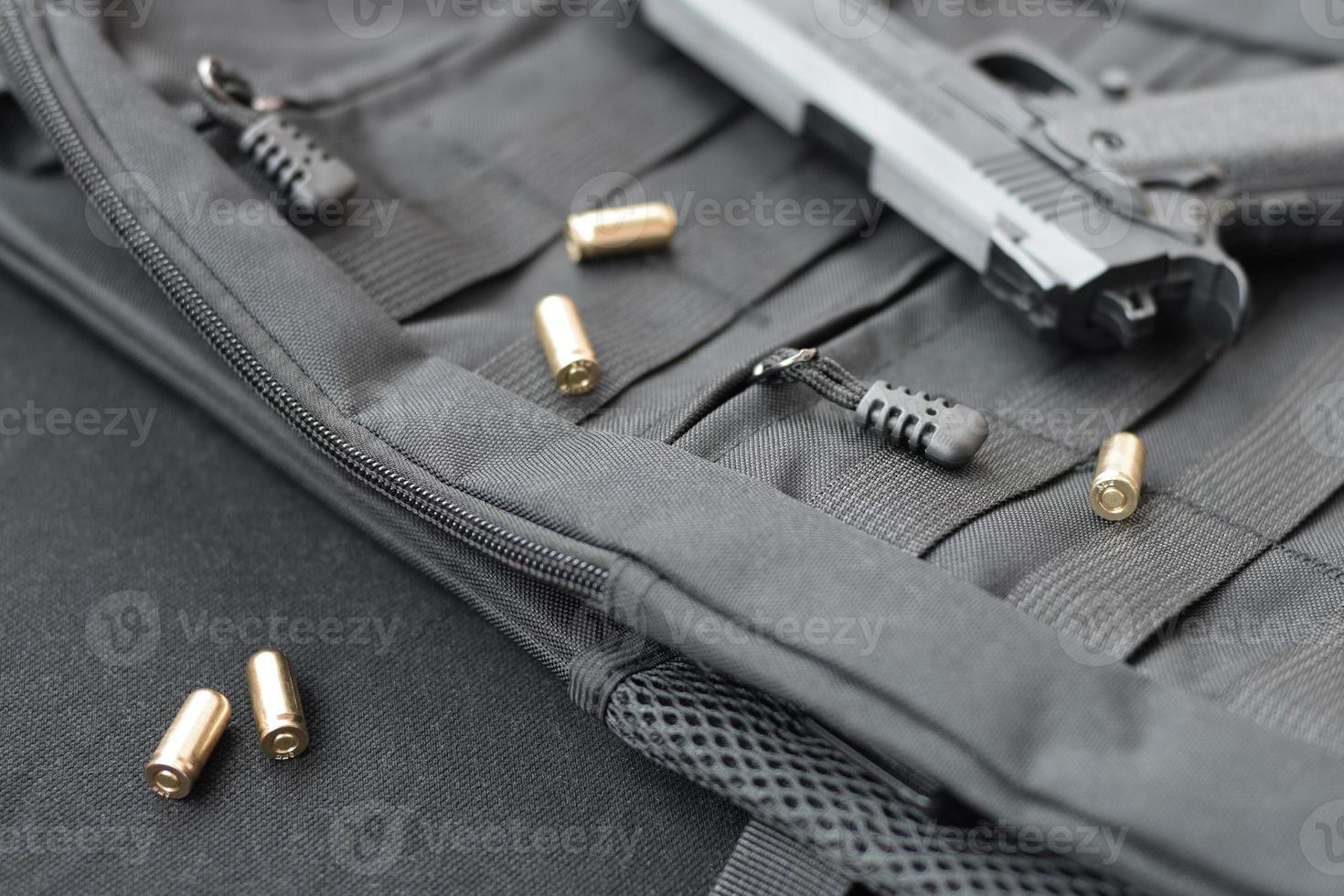 9mm bullets and pistol lie on a black tactical backpack photo