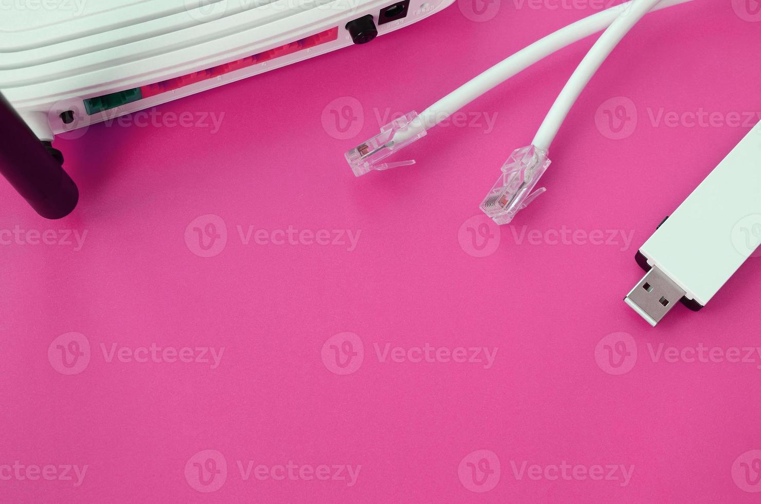 Internet router, portable USB wi-fi adapter and internet cable plugs lie on a bright pink background. Items required for internet photo
