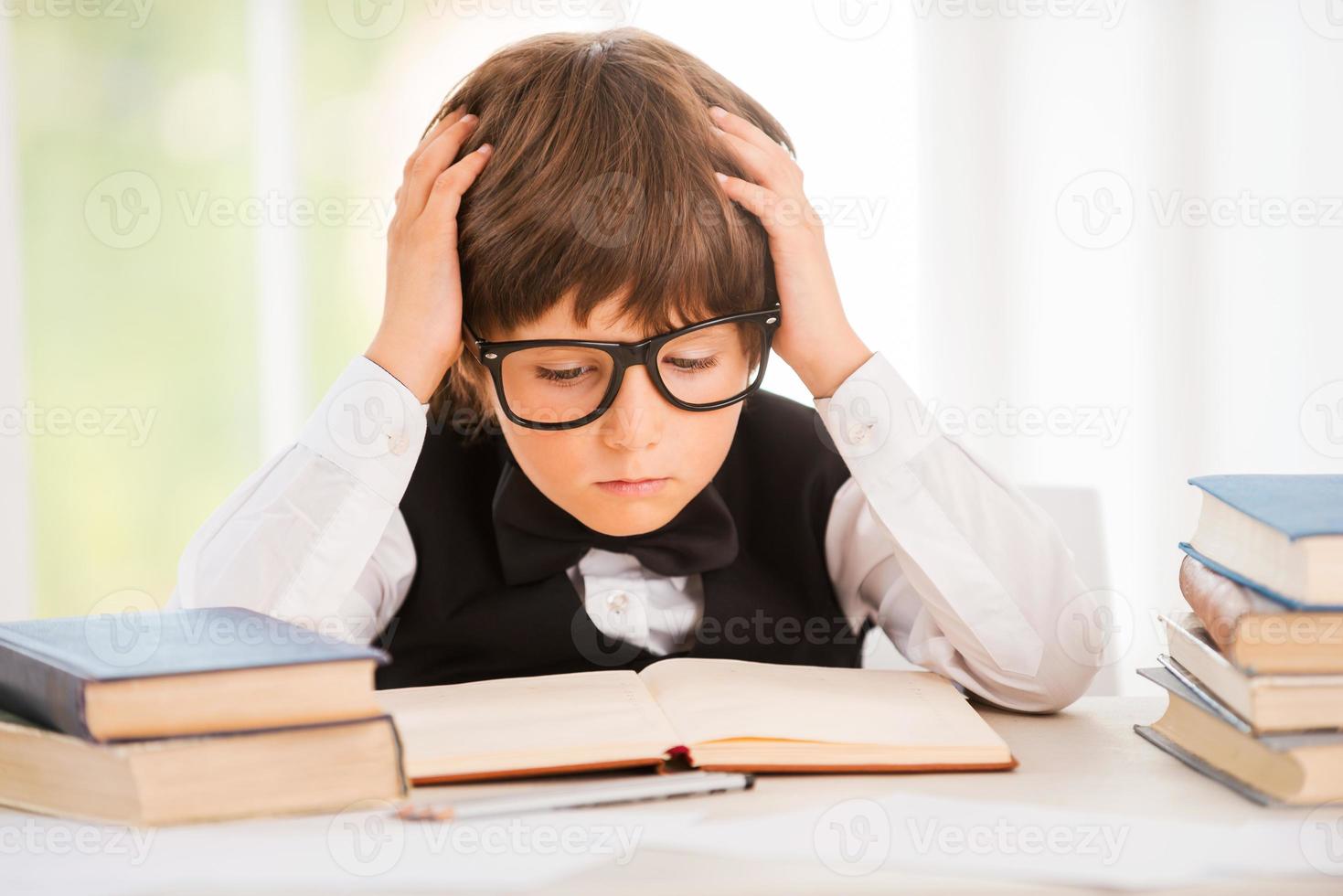 Concentrated on studying. Cute young boy making research while sitting at the desk photo