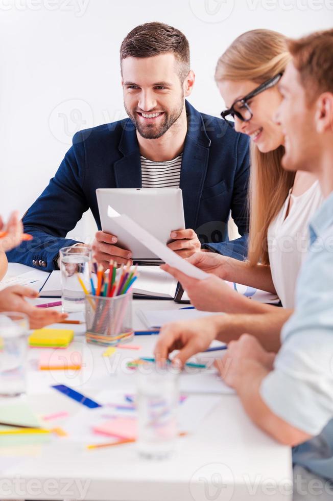 Working moments. Group of business people in smart casual wear sitting together at the table and smiling photo