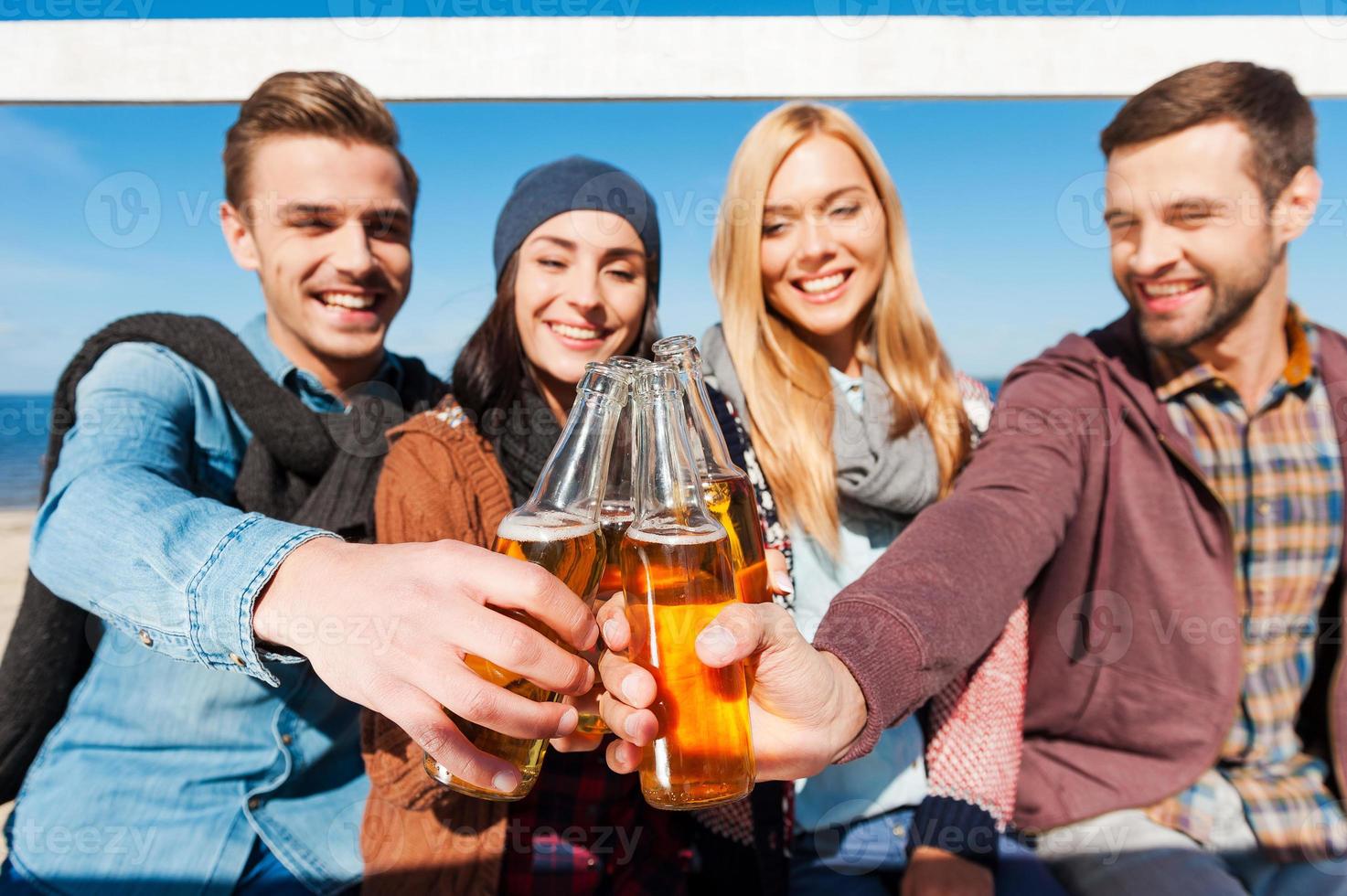 aplausos a un grupo de amigos de jóvenes alegres animando con cerveza y sonriendo mientras se unen entre sí foto