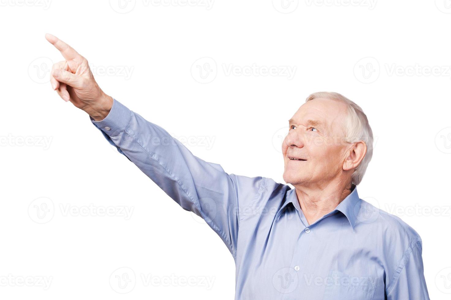 Look over there Happy senior man pointing away and smiling while standing against white background photo