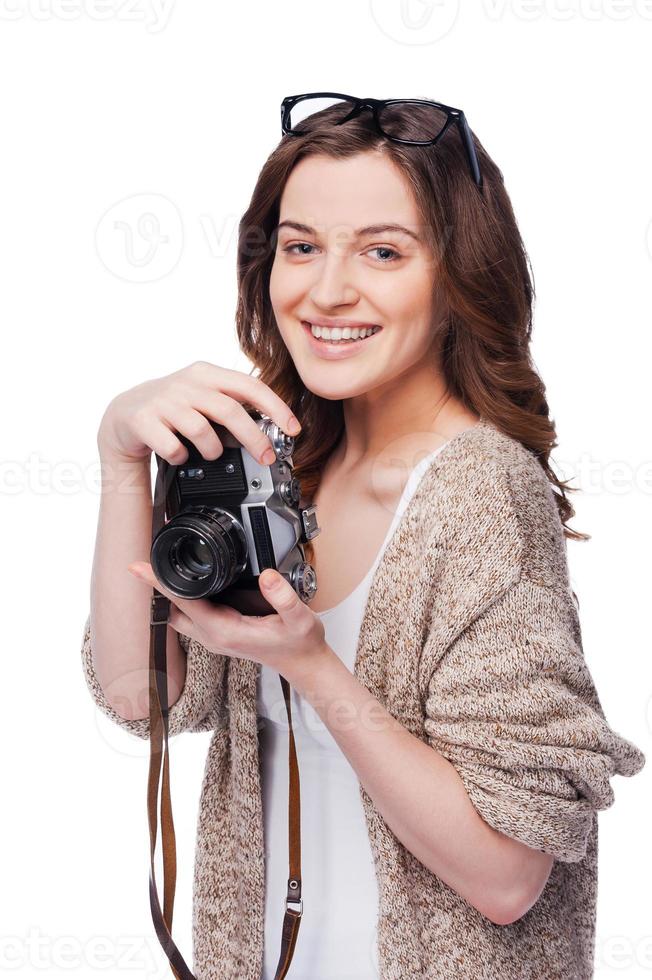 Confident photographer. Beautiful young smiling woman holding camera while standing isolated on white photo