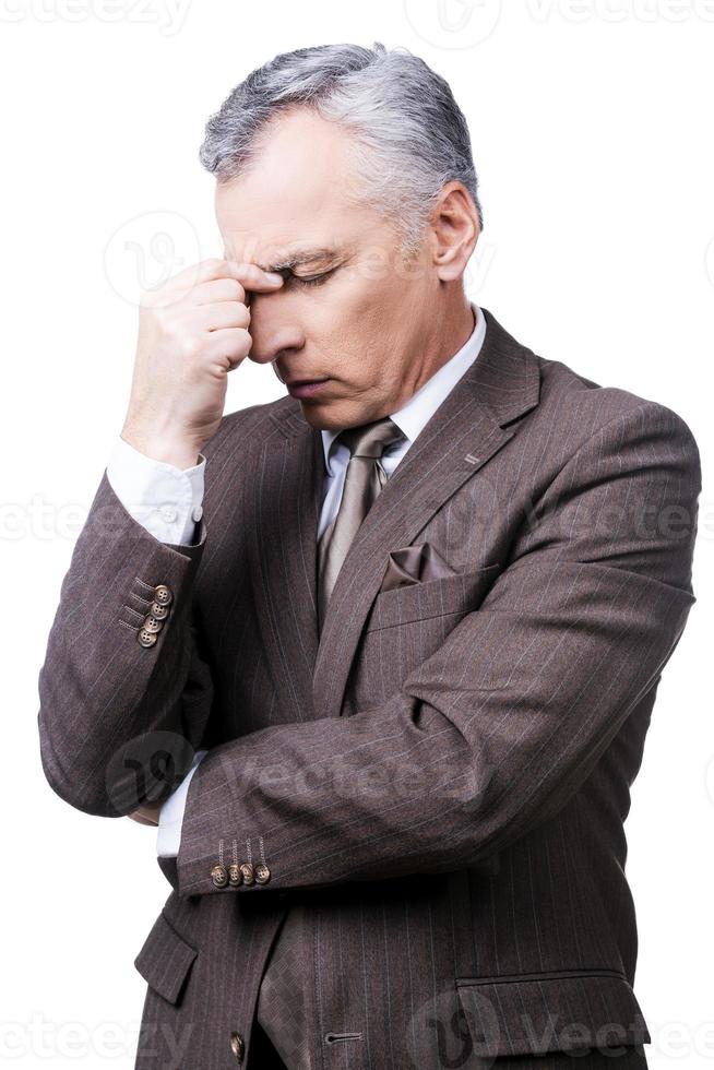 Too stressful day. Frustrated mature man in formalwear touching head with fingers and keeping eyes closed while standing against white background photo