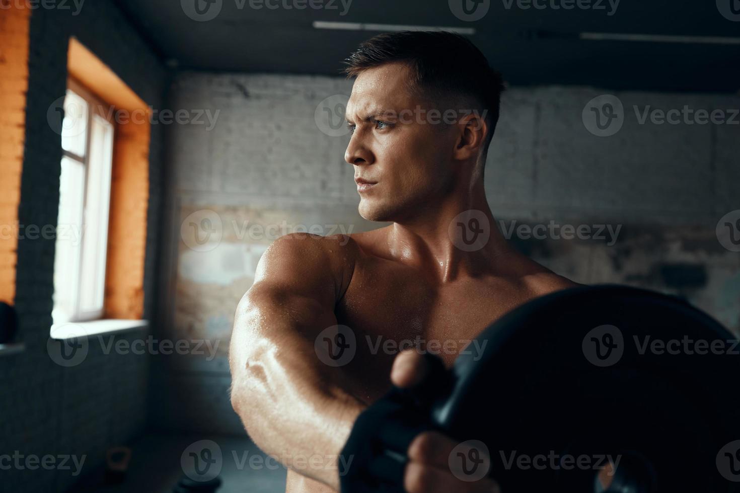 Handsome young man looking concentrated while doing weight training in gym photo