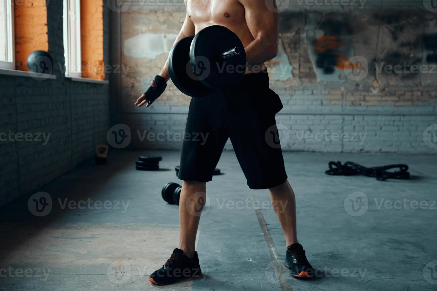 Unrecognizable muscular man training with dumbbell in gym photo