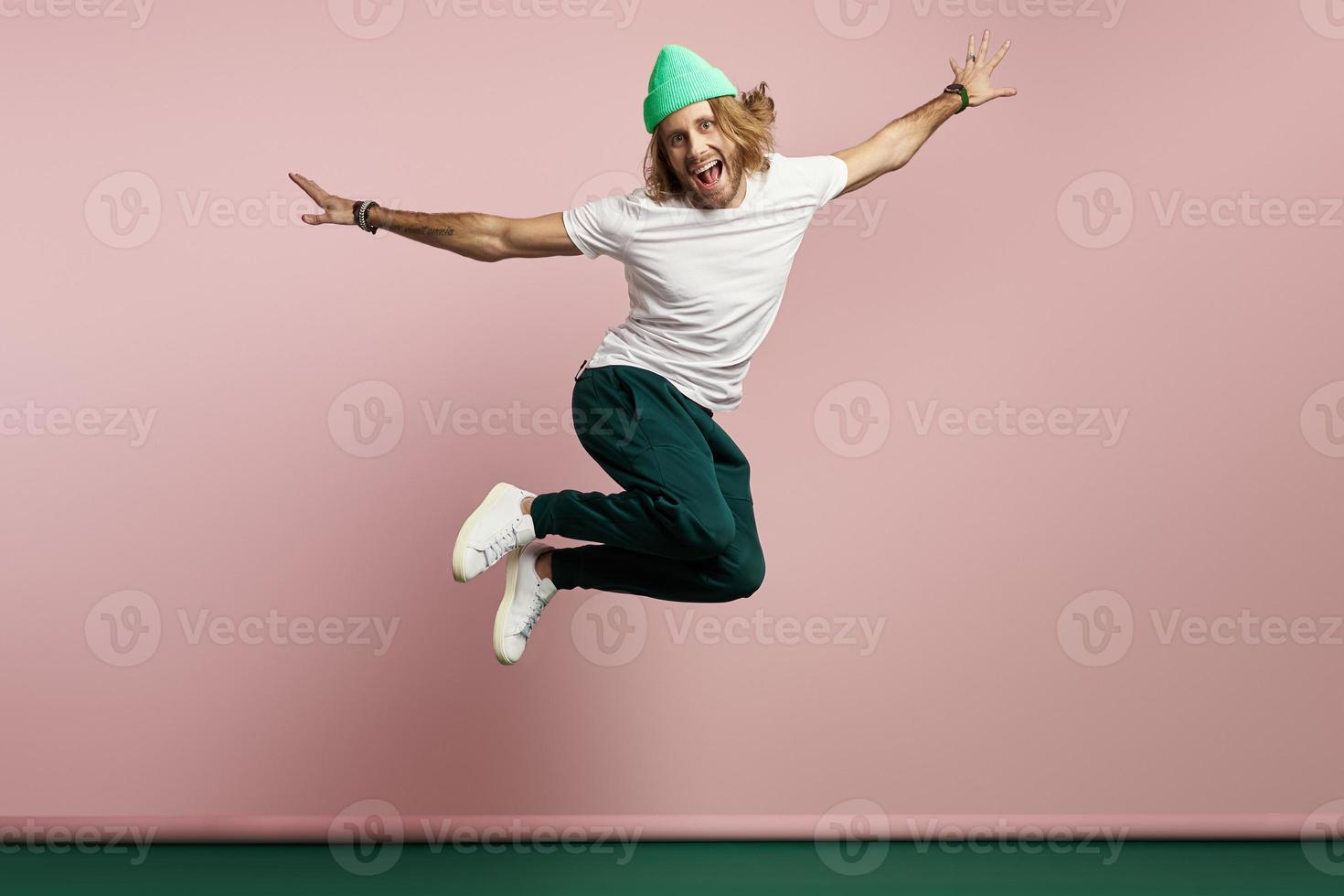 Handsome young man looking happy while jumping against colorful background photo
