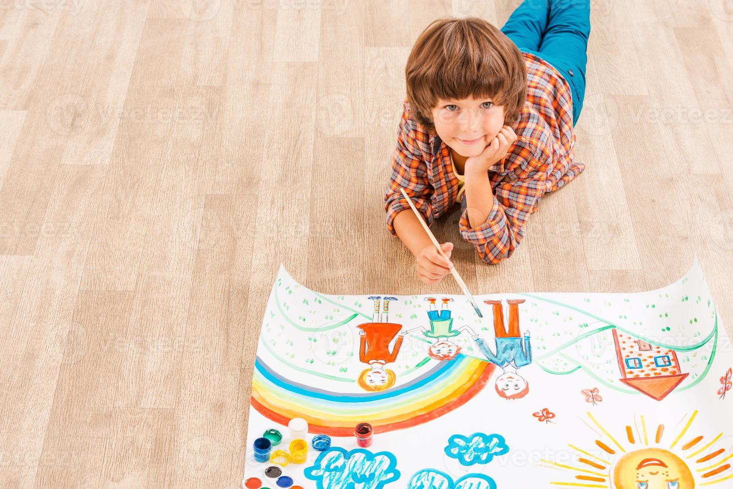 buscando inspiración. niño relajándose mientras pinta con acuarelas en el suelo foto