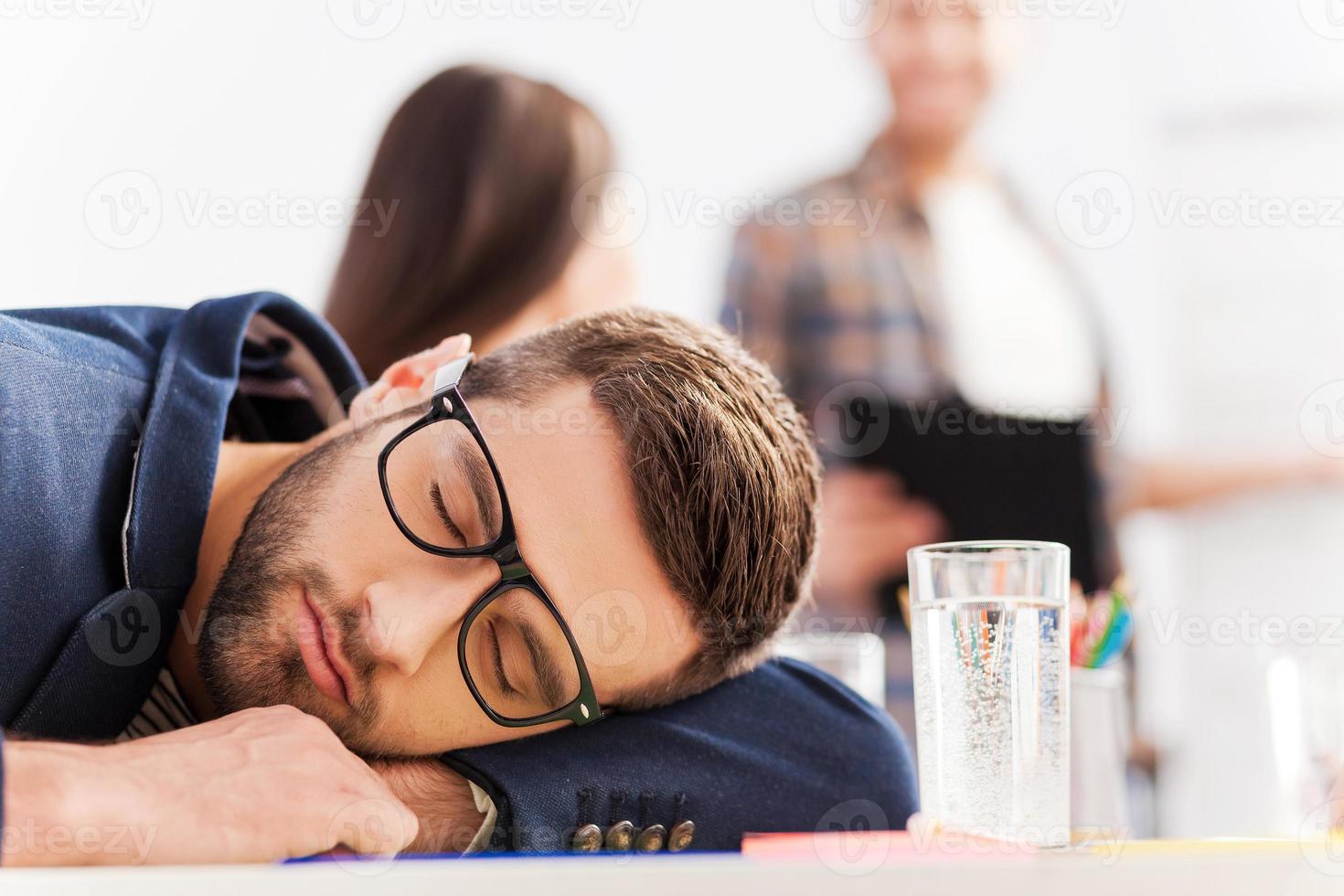 Tired businessman. Tired young businessman sleeping while sitting at his working place and leaning his head at the desk photo