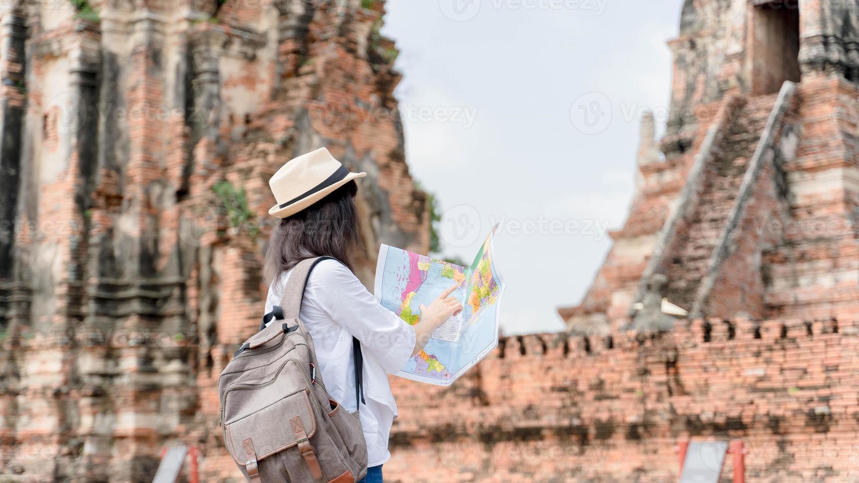 Hipster woman traveler with backpack holding map and exploring on temple, travel concept, space for text. wanderlust photo