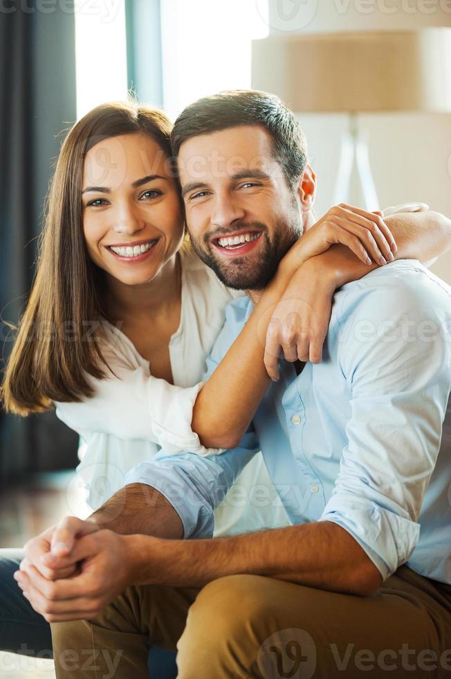 felices de estar juntos. hermosa joven pareja amorosa sentada en el sofá mientras una mujer abraza a su novio y sonríe foto