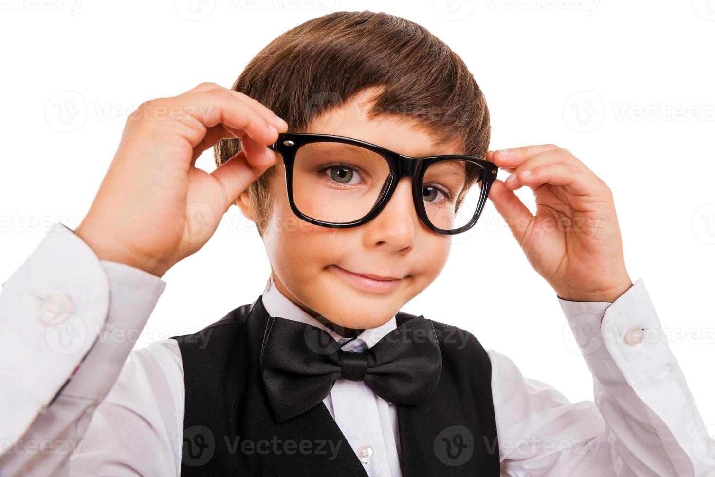 Little Nerd. Wide angle image of cute little boy adjusting his glasses and looking at camera while isolated on white photo