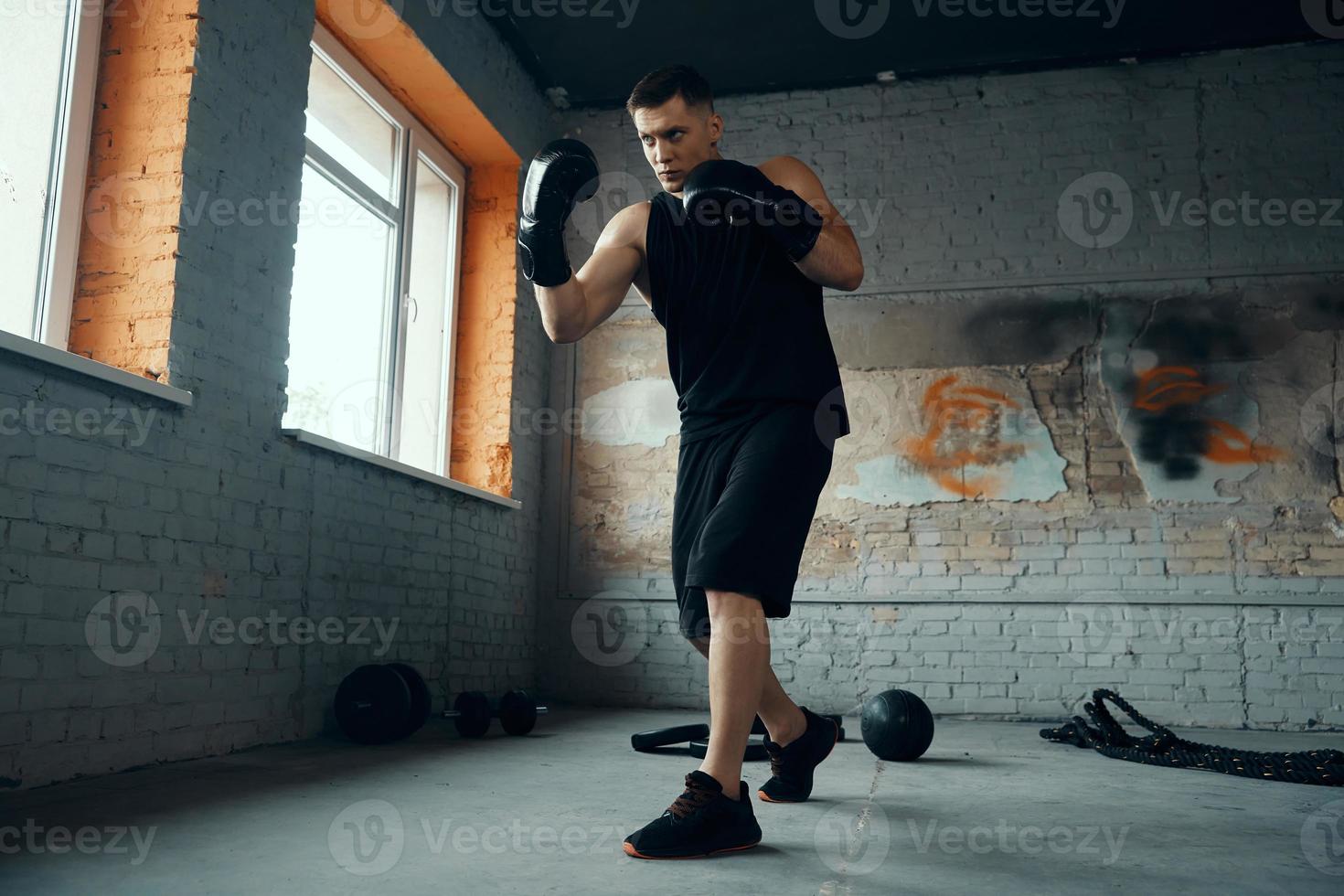 Fit young man practicing in punching while standing in gym photo