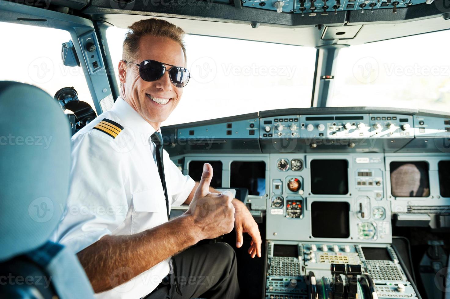 listo para volar. vista trasera de un piloto masculino confiado que muestra su pulgar hacia arriba y sonríe mientras está sentado en la cabina foto